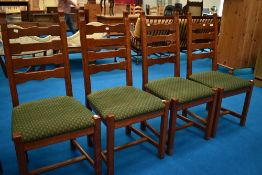 A set of four modern oak ladder back dining chairs having upholstered seats