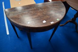 An Edwardian mahogany demi lune fold over card table