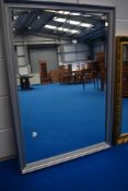 A modern overmantel or wall mirror having silvered effect frame