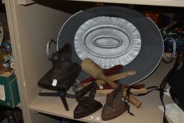 A vintage tin bath of small proportions, three cast iron flat irons , a posser, two pairs of laundry