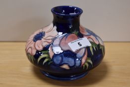 A William Moorcroft tube lined anemone vase of squat form, on blue ground, measuring 11.5cm tall