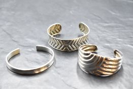 Three silver cuff bangles of various forms