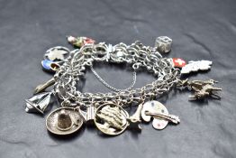 A silver fancy link charm bracelet having sixteen white metal and silver charms including ski