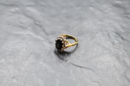 A sapphire and diamond cluster ring having an oval sapphire surrounded by ten small diamonds in an