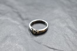 An artisan style diamond trilogy ring having a central diamond in collared mount flanked by two
