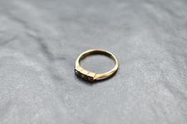 A diamond trilogy ring having three diamond chips in an Art Deco style mount on a yellow metal