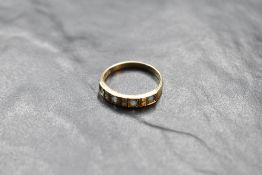 A four stone blue topaz ring interspersed by three pairs of small diamonds in a half eternity