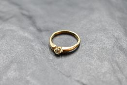 A diamond solitaire ring, approx 0.125ct in a claw set mount to bar set moulded shoulders on an 18ct