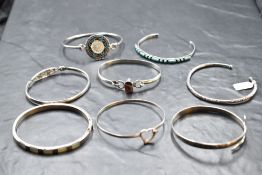 Eight silver bangles of various forms including Egyptian serpent, Mexican Aztec, Rennie Macintosh