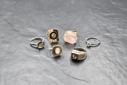 Six silver and white metal rings of various forms, including rose quartz, moonstone, rock crystal,