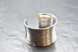 A large silver cuff bangle having linear decoration, approx 100g & 43mm wide