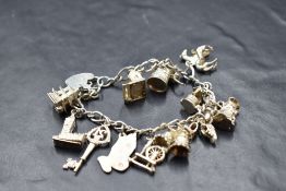 A silver charm bracelet having padlock clasp and thirteen white metal and silver charms including