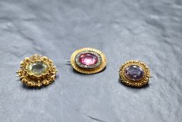 Three vintage yellow metal brooches of oval form, all having central stones in decorative mounts, no