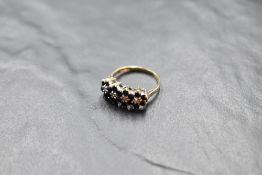 A sapphire and diamond chip quadruple cluster ring having a claw set raised mount on a 9ct gold