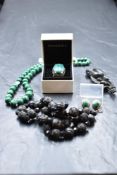A vintage jewellery case containing a string of mourning beads, brooch, string of malachite beads