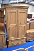 A natural pine wardrobe having drawer base