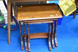 A reproduction walnut and mahogany nest of three tables