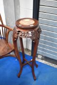 An oriental hardwood plant stand having marble inset top