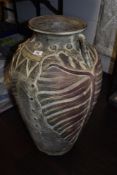 A large terracotta floor vase, with handles to both sides and leaf like design.