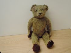 A mid 20th century straw filled yellow plush Teddy Bear having growling mechanism, plastic eyes,