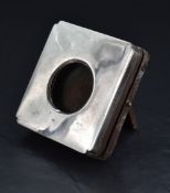 A George V silver mounted watch holder, of hinged square form with re-entrant corners, opening by