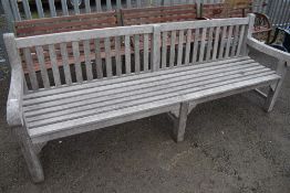 A traditional teak garden bench of very long proportions (one of two) length approx 240cm