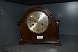 A 1930s oak arched mantel clock, having spindles to side with brass finials and feet.