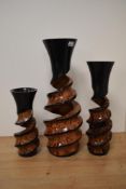 Three carved mango wood art vases, having twist stems with semi open bodies.