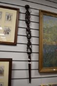 A vintage African carved walking cane, depicting heads.