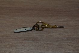 A miniature pair of gold tone sewing scissors in the form of a stork, with boned handled knife