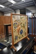 A traditional oak frame embroidered firescreen