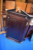 A 19th Century mahogany corner cupboard having brass eagle finial
