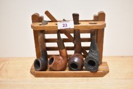 A vintage pipe rack in the form of a gate, sold with four pipes, including tug boat and Special R.