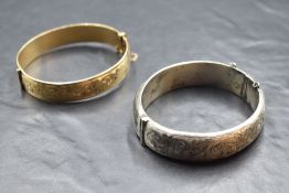An HM silver hinged bangle having engraved decoration and a similar gold plated hinged bangle