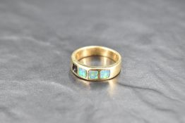 A yellow metal band ring stamped 585 having four inset black opal panels, one missing, size U &