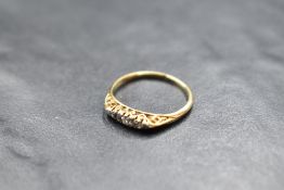 A dainty five stone graduated diamond ring in a boat shaped gallery mount on a yellow metal loop