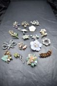 A black jewellery case containing a selection of silver brooches including enamelled, pearl,