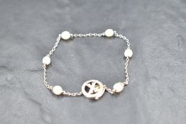 A white metal bracelet having six inset baroque pearls on a fine chain with a diamond set circular