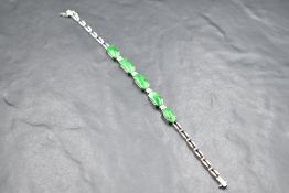 An 18ct white gold articulated bracelet having five oval jade style panels interspersed by four