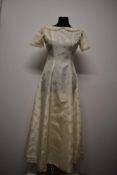 A mid to late 1950s wedding dress, having short sleeves and Peter Pan collar with braided edge.