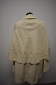 A 1920s cream childs cape, having hand worked silk embroidery.