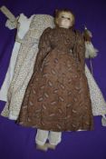 A circa 1820s doll, having plaster hand painted head with glass eyes, having original clothes and