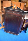 A 19th Century mahogany corner cupboard having brass eagle finial