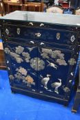 A Japanesque black laquered side cabinet with applique crane decoration