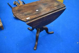 A 19th Century low pedestal table having drop flap top on turned column and triple splay legs