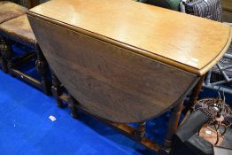 An early 20t Century golden oak drop leaf table