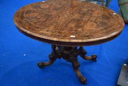 A Victorian walnut breakfast table having inlaid oval top on tilt top mechanism