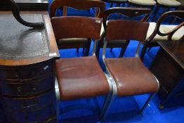 A pair of vintage chairs having metal frames and textured vinyl seats