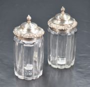 A pair of George IV silver topped crystal condiments, the domed flame final topped covers within a