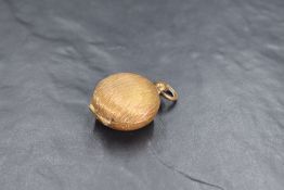 A small gilt metal coin holder, of hinged circular form with textured surface 3cm diameter.
